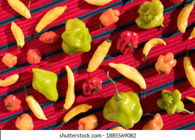 Assorted Colorful Chili Peppers In A Pattern On A Red Table Cloth (Overhead)