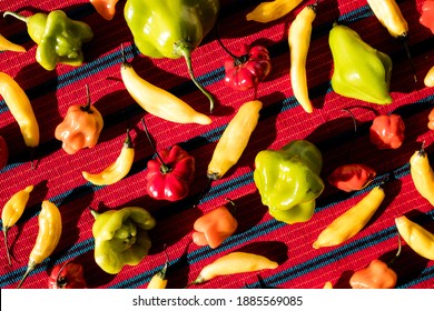 Assorted Colorful Chili Peppers In A Pattern On A Red Table Cloth (Overhead)