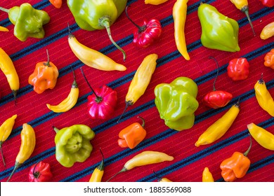 Assorted Colorful Chili Peppers In A Pattern On A Red Table Cloth (Overhead)