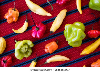 Assorted Colorful Chili Peppers In A Pattern On A Red Table Cloth (Overhead)