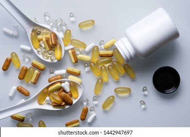 Assorted colorful pills, a spoon full of them and opened bottle on white background.  Medical concept. 