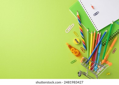 Assorted colorful school supplies including notebooks, pencils, pens, and paper clips on a green background. Back to school theme - Powered by Shutterstock