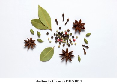 Assorted colorful spices peppercorns, bay leaf, cardamom, anise, clove on white background.