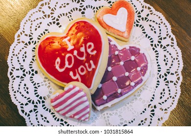 Assorted cookies with colored glaze in the shape of a heart with the word love on a white napkin Valentine's Day