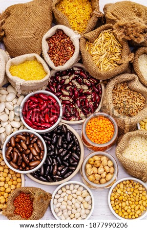 Assorted different types of beans and cereals grains. Set of indispensable sources of protein for a healthy lifestyle. White wooden boards background, top view