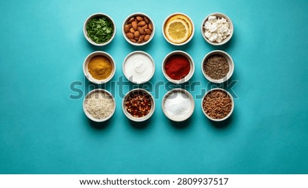 Assorted dried spices and herbs in small bowls on turquoise background