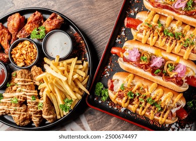 Assorted fast food items including hot dogs, chicken strips, and fries on a platter with dipping sauces. Perfect for a casual meal or party snack. - Powered by Shutterstock