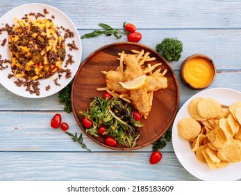 Assorted fastfood loaded Cheesy Fries, Battered Cod Fish, Nacho With Cheese Served in dish isolated on wooden table top view fastfood