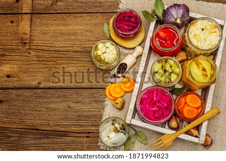 Assorted of fermented vegetables in glass jars. Preserved season vegetables concept, probiotics food for healthy lifestyle. Vintage wooden table, top view