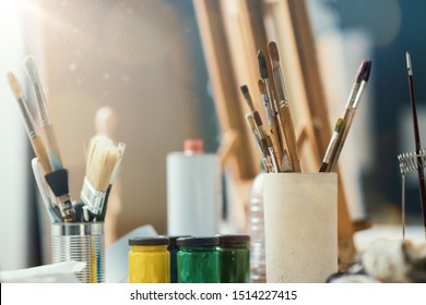 Assorted Fine Arts Supplies For Painting On A Desk In The Art Studio, Oil And Acrylic Paint