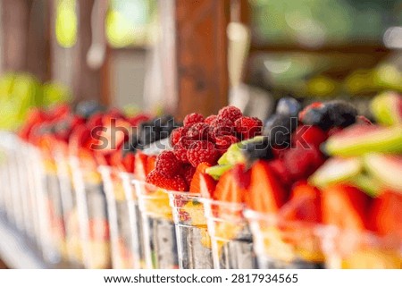 Assorted fresh cut fruit pieces in clear plastic cups arranged on store shelves. Healthy fruit salad cups are ready for sale. Food
