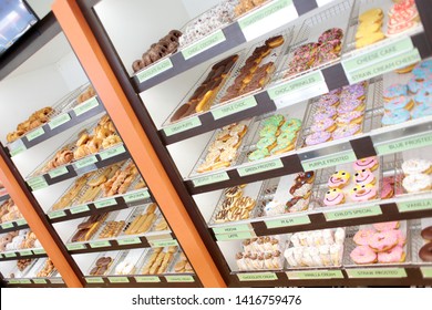 Assorted fresh donuts on display racks at the donut shop.
