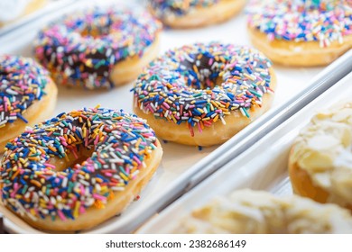 Assorted fresh donuts on display racks at the donut shop.Display of delicious pastries with assorted glazed donuts in shop.Various donuts on shelf in Bakery.Colorful flavor donuts with coating,topping - Powered by Shutterstock