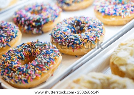 Assorted fresh donuts on display racks at the donut shop.Display of delicious pastries with assorted glazed donuts in shop.Various donuts on shelf in Bakery.Colorful flavor donuts with coating,topping