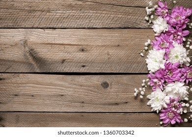 Assorted fresh flowers composition as border on rustic old wooden background. Top view point.