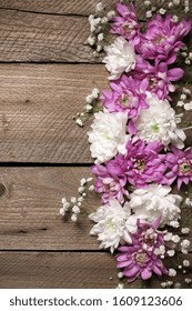 Assorted fresh flowers composition as border on rustic old wooden background. Top view point.