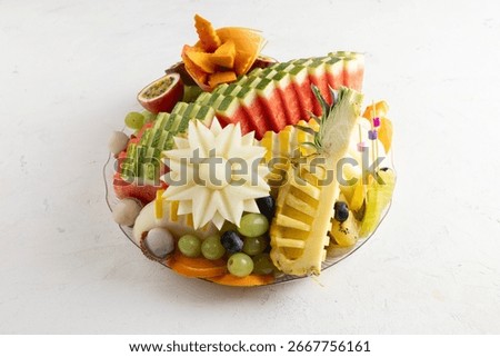 Assorted fresh fruit platter with watermelon, pineapple, melon, mango, grapes, passion fruit, kiwi, orange slices, lychee, dates, and blueberries. Decorative tropical fruit arrangement