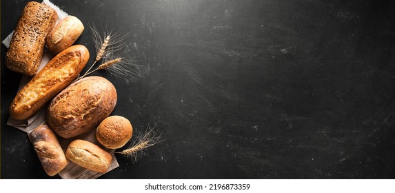 Assorted  freshly baked bread on black background, banner, copy space. Variety of artisan bread and ears of wheat. - Powered by Shutterstock