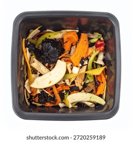 Assorted fruit and vegetable scraps including carrots, apples, and dark matter in a black compost bin, isolated on a white background.