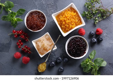 Assorted Fruit Yellow, Black And Orange Caviar In A White Bowl With Raspberries, Blueberries, Currants And Herbs On A Gray Background. Background Image. Flatlay, Top View