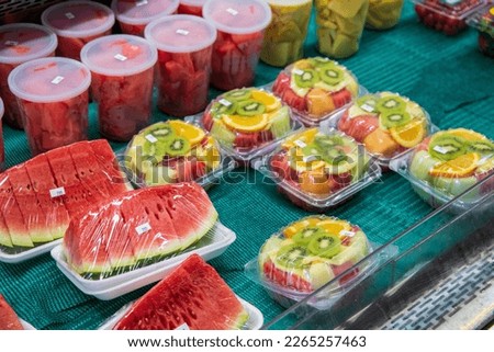 assorted fruits in plastic clamshell containers and cut watermelons wrapped in cellophane plastic at the Municipal Market in Atlanta Georgia USA