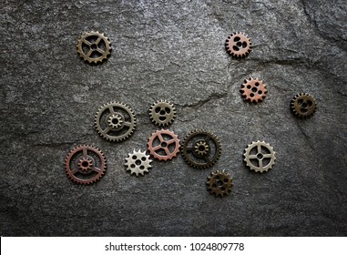 Assorted Gears Spread Out On Textured Background -- Gears Are Not Connected, Could Be Lack Of Coordination Or Miscommunication Concept