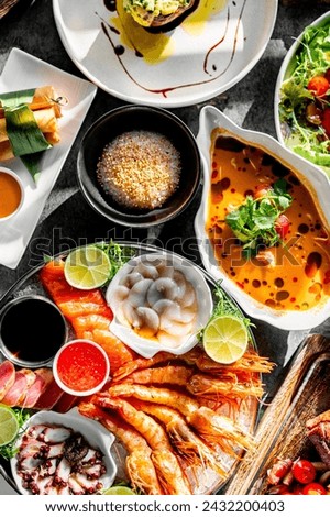 assorted gourmet dishes, including fresh seafood, salads, and soups. The arrangement features shrimp, soup, rice or grain, salads, sushi rolls, and other delectable treats on a dark table surface