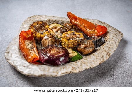 Assorted grilled vegetables including corn, mushrooms, zucchini, onion and sweet pepper served on a rustic plate, presented as a modern plant based restaurant dish.
