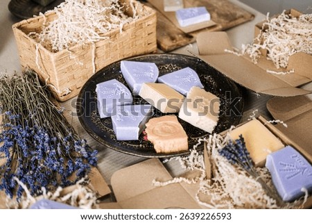 Assorted handmade soap bars displayed on a plate with dried lavender and kraft packaging. Lavender soap, natural skincare, essential oils, botanical self-care