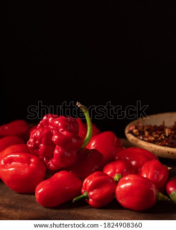 Assorted hot chilli pepper and crushed peppers on wooden surface with dark moody background. Ideal for food recipe or restaurant menu