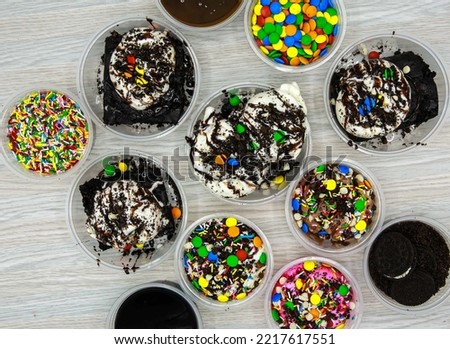 assorted ice cream include vanilla, chocolate, mango, strawberry, brownie, , syrup and chips served in disposable cup top view of indian and pakistani dessert