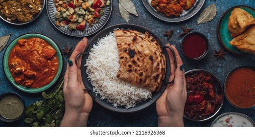 Assorted Indian Ethnic Food Buffet On Rustic Concrete Table From Above: Curry, Fried Samosa, Rice Biryani, Dal, Paneer, Chapatti, Naan, Chicken Tikka Masala, Traditional Dishes Of India For Dinner