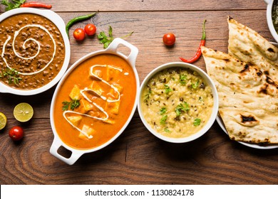 Assorted indian food for lunch or dinner, rice, lentils, paneer, dal makhani, naan, chutney, spices over moody background. selective focus
