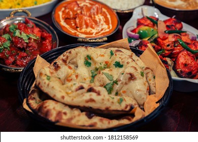 Assorted Indian Food For Lunch Or Dinner, Rice, Lentils, Paneer Butter Masala, Palak Panir, Dal Makhani, Naan, Green Salad, Spices Over Moody Background. Selective Focus