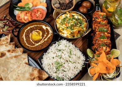 Assorted Indian food on wooden background. Dishes and appetizers of Indian cuisine. Group of Indian food Curry, butter chicken, rice, biryani, paneer, tikka, naan, salad, dessert, chutney and spices. - Powered by Shutterstock