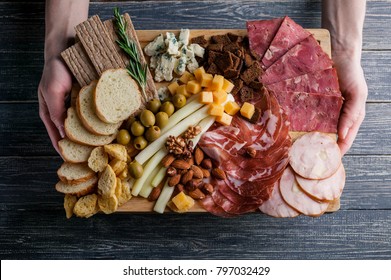 Assorted From Meat And Cheese On A Chopping Board. Smoked Sausage, Meat Roll From A Turkey With Cheese, Jamon, Olives, Nuts And Various Grades Of Cheese. Soft Focus. Low Key.