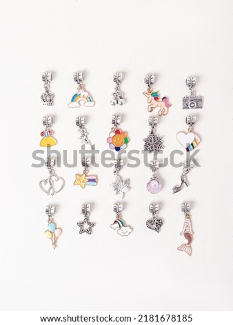 Assorted metal charms for bracelets on white background. Mermaid, heart, snowflake, heart. Creating jewelry