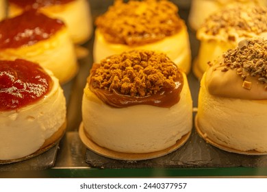 Assorted mini cheesecakes with fruit topping and caramel drizzle on display in a bakery - Powered by Shutterstock