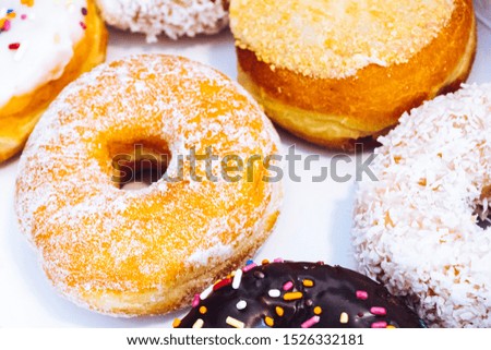 Assorted multicolored donuts in a bakery box with chocolate frosted, glazed and sprinkles donuts. Sugar addiction or festive menu concept