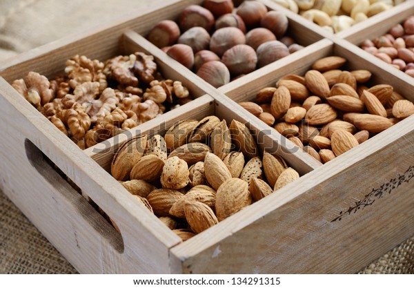 Assorted nuts in\
rusted wooden box - walnut, almond, hazelnut, cashew and peanuts\
placed on burlap\
background