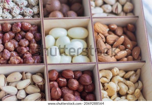 Assorted nuts in a wooden box. Set\
of almonds, peanuts, cashews pistachios macadamia\
hazelnuts.
