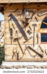Assorted old rusty metal work tools on wooden wall. Vintage rusty household tools hang on the wall