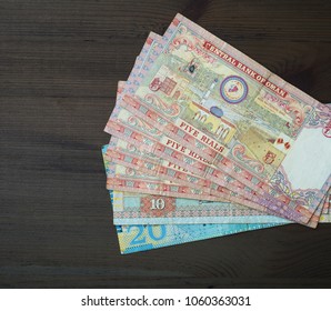 Assorted Omani Riyal Bank Currency Notes Spread On Black Background.