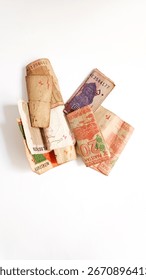 Assorted Pakistani currency notes isolated on white background. Close-up of rolled and folded banknotes including 10, 20 and 50 rupees, symbolizing finance, economy, banking, savings, and investment.