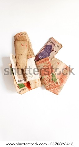 Assorted Pakistani currency notes isolated on white background. Close-up of rolled and folded banknotes including 10, 20 and 50 rupees, symbolizing finance, economy, banking, savings, and investment.