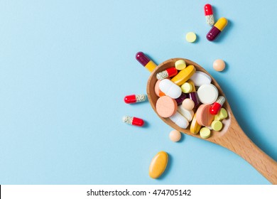 Assorted pharmaceutical medicine pills, tablets and capsules on wooden spoon