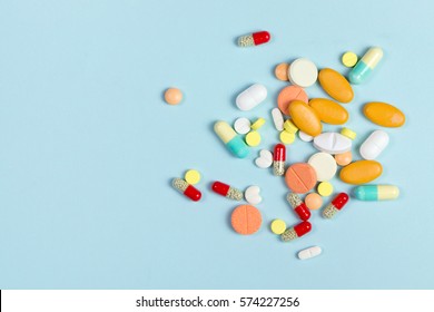 Assorted pharmaceutical medicine pills, tablets and capsules over blue background