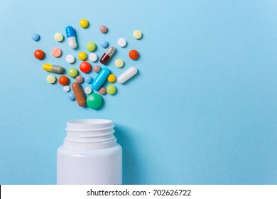 Assorted Pharmaceutical Medicine Pills, Tablets And Capsules And Bottle On Blue Background. Copy Space For Text