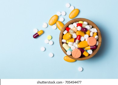 Assorted pharmaceutical medicine pills, tablets and capsules on wooden bowl
