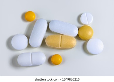 Assorted pharmaceutical pills. White, yellow - orange tablets in different shapes. Drugs scattered on a white background. Close up.